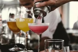 A bartender expertly pours a delicious cocktail into a glass, creating a tantalising drink.