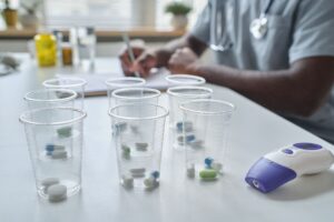 Close-up of plastic cups with pills inside of them standing on the table at hospital with doctor in the background