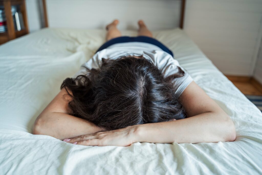 Sad, unhappy woman lying on bed in depression.