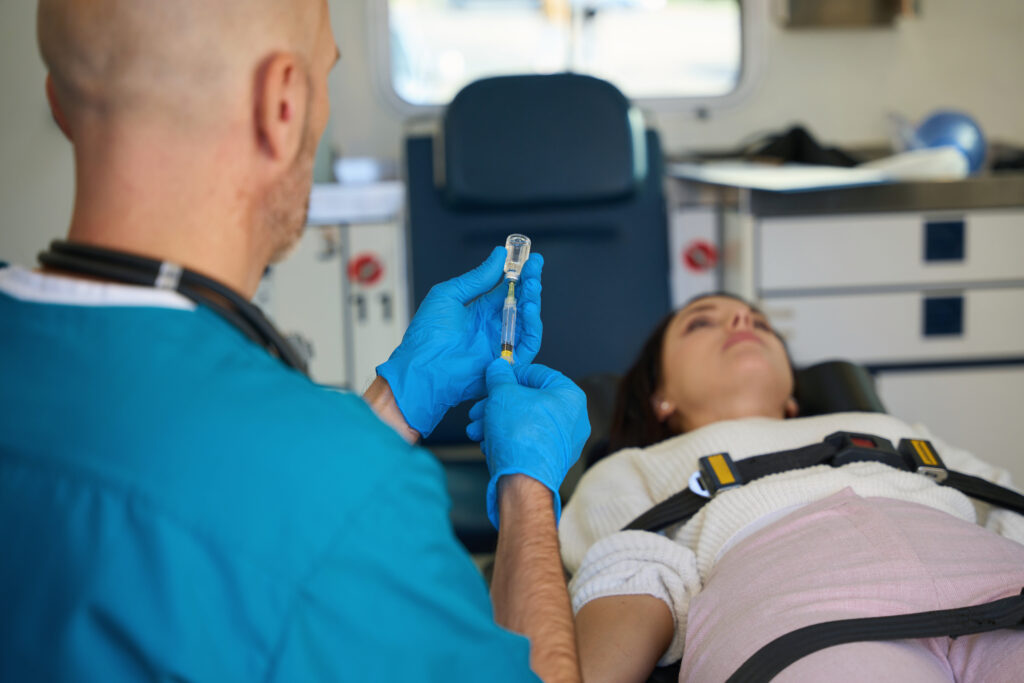 Doctor preparing syringe for injection to woman on a gurney