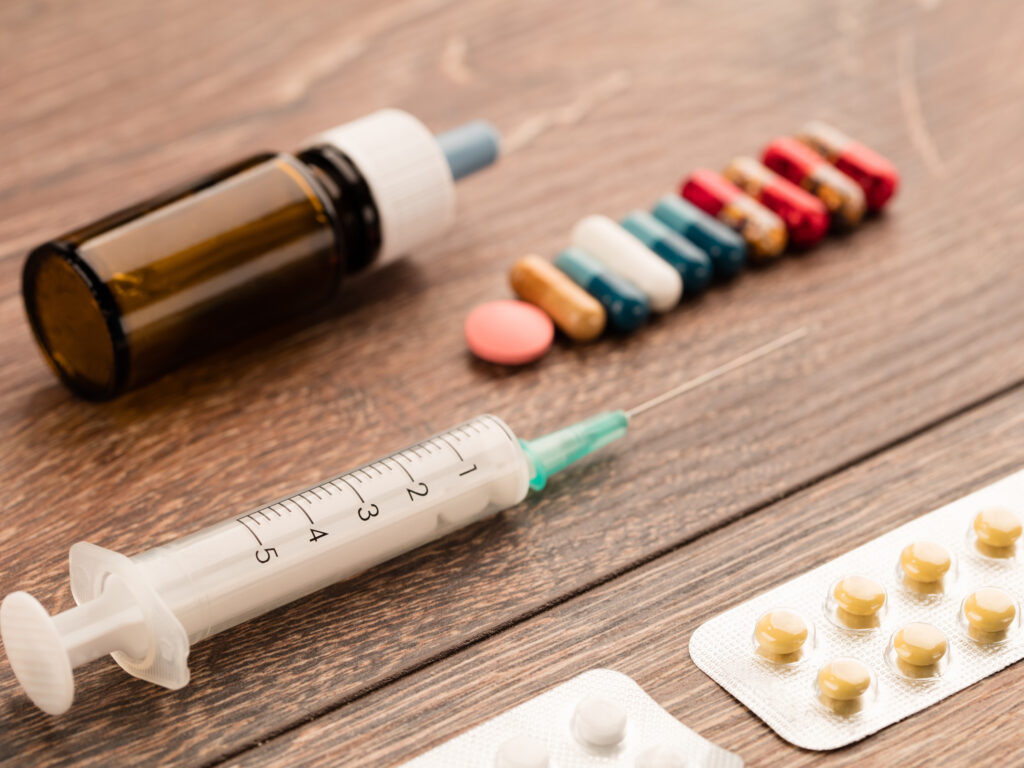 various medications, Syringe, capsules, pills, and medical bottle on a wooden table