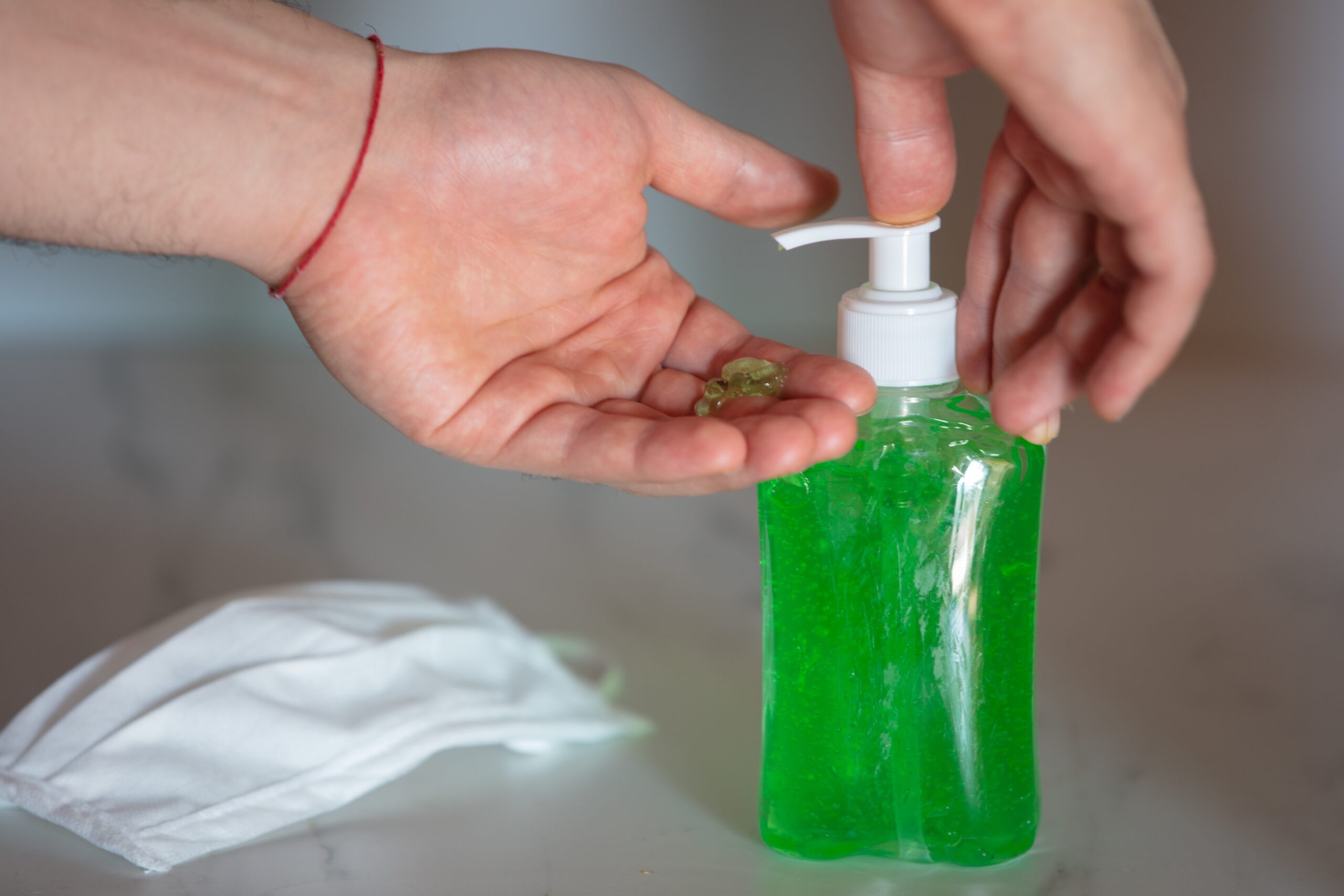 Closeup of a person using liquid soap on the table near a face mask coronavirus concept