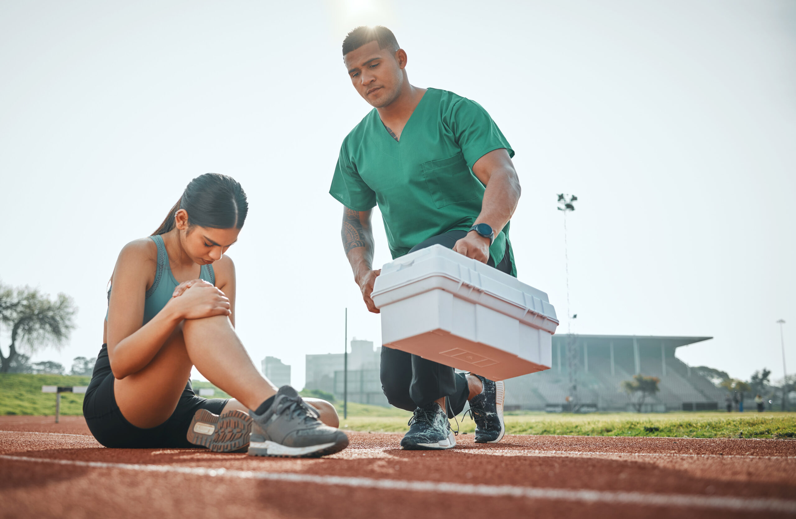 Shot of a sports paramedic providing first aid to an athlete on a running track.