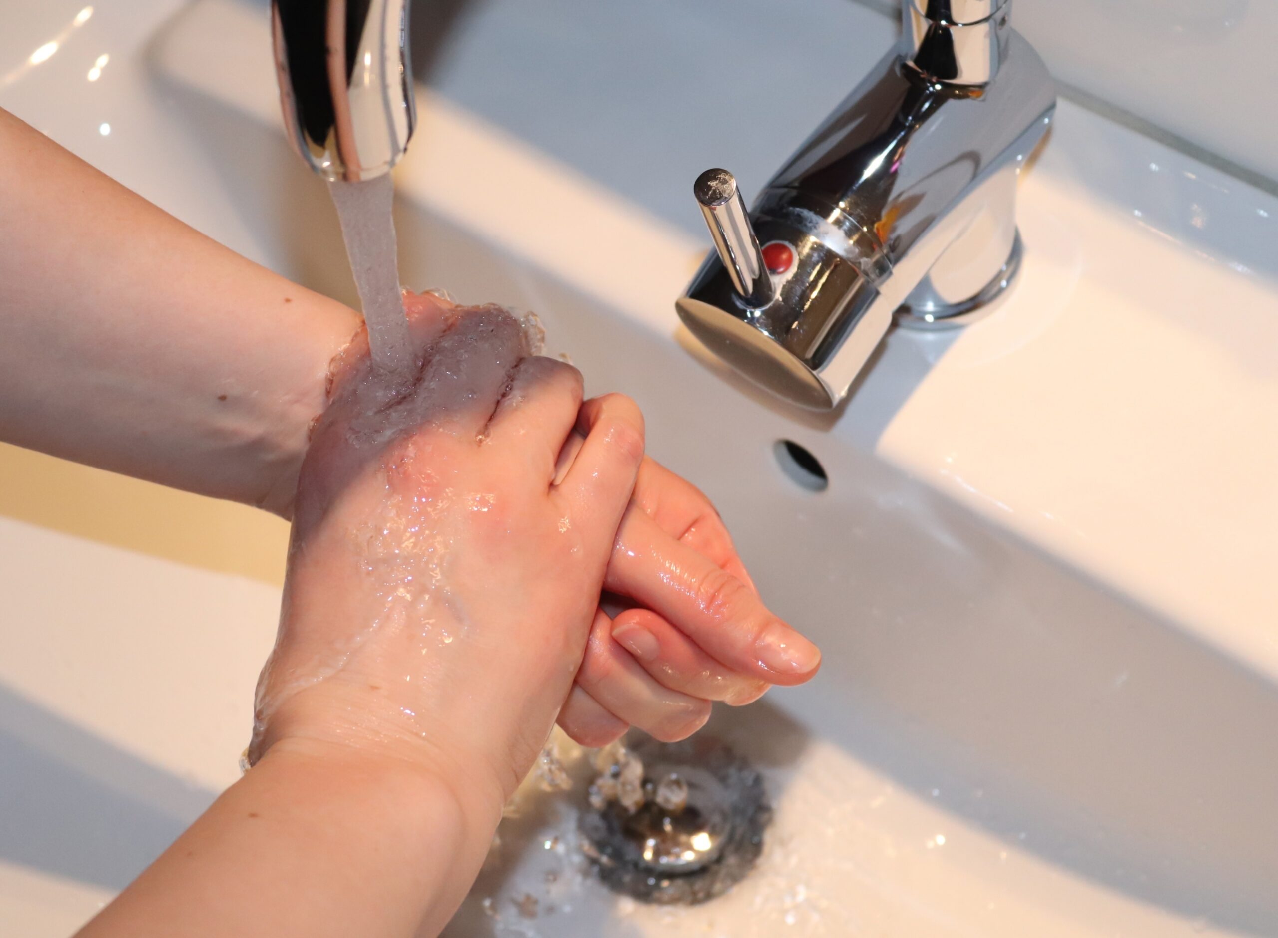A woman washing hands with soap under the tap with water - hygiene concept