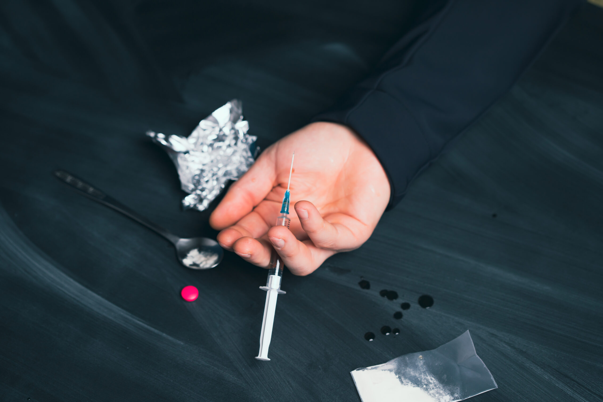 Drug addict reaches for another dose of drug. Concept of addiction, antidrug. International Day against Drug Abuse.