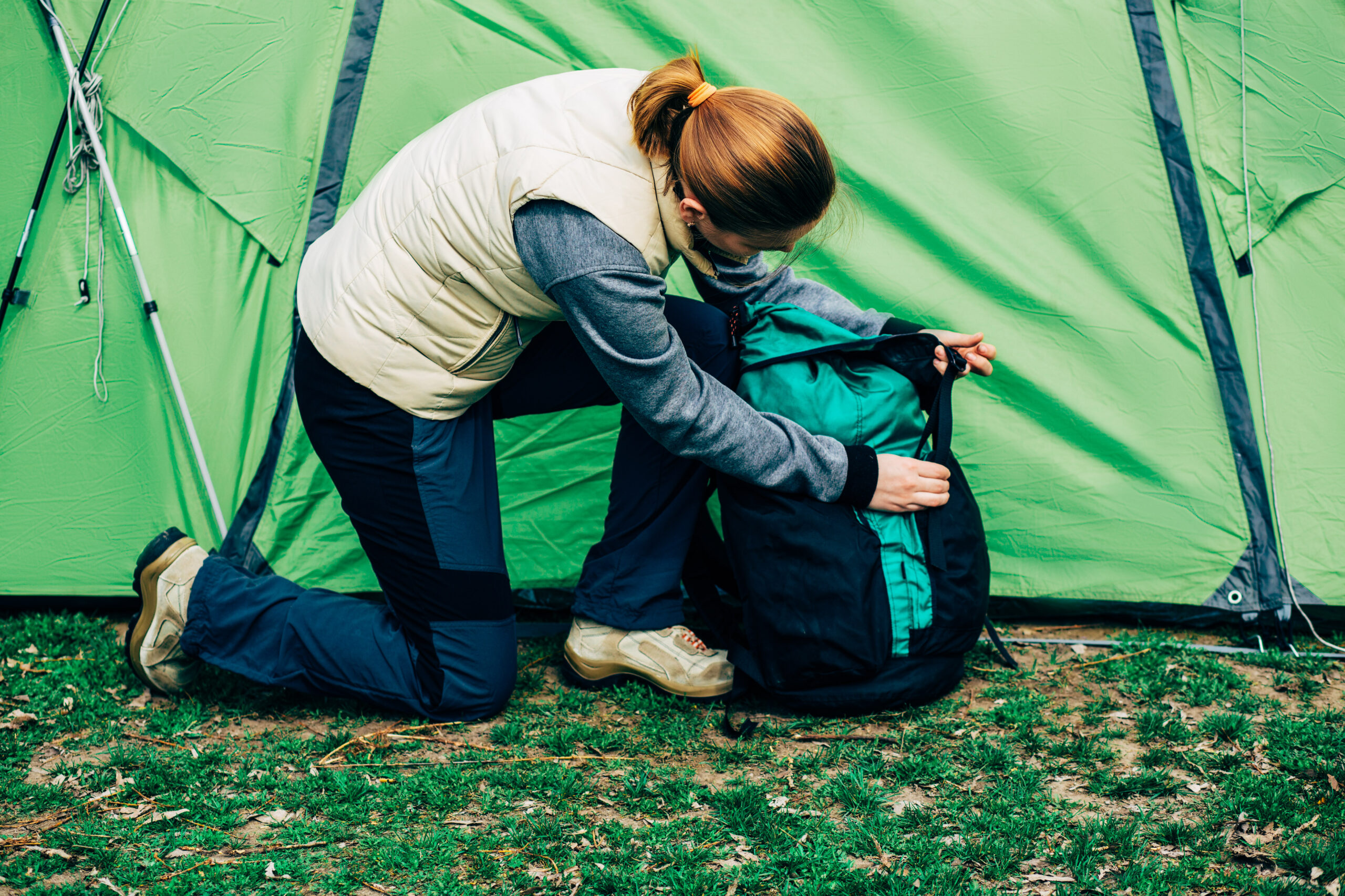 female unpack a backpack near tent, after a long day of hiking and backpacking.