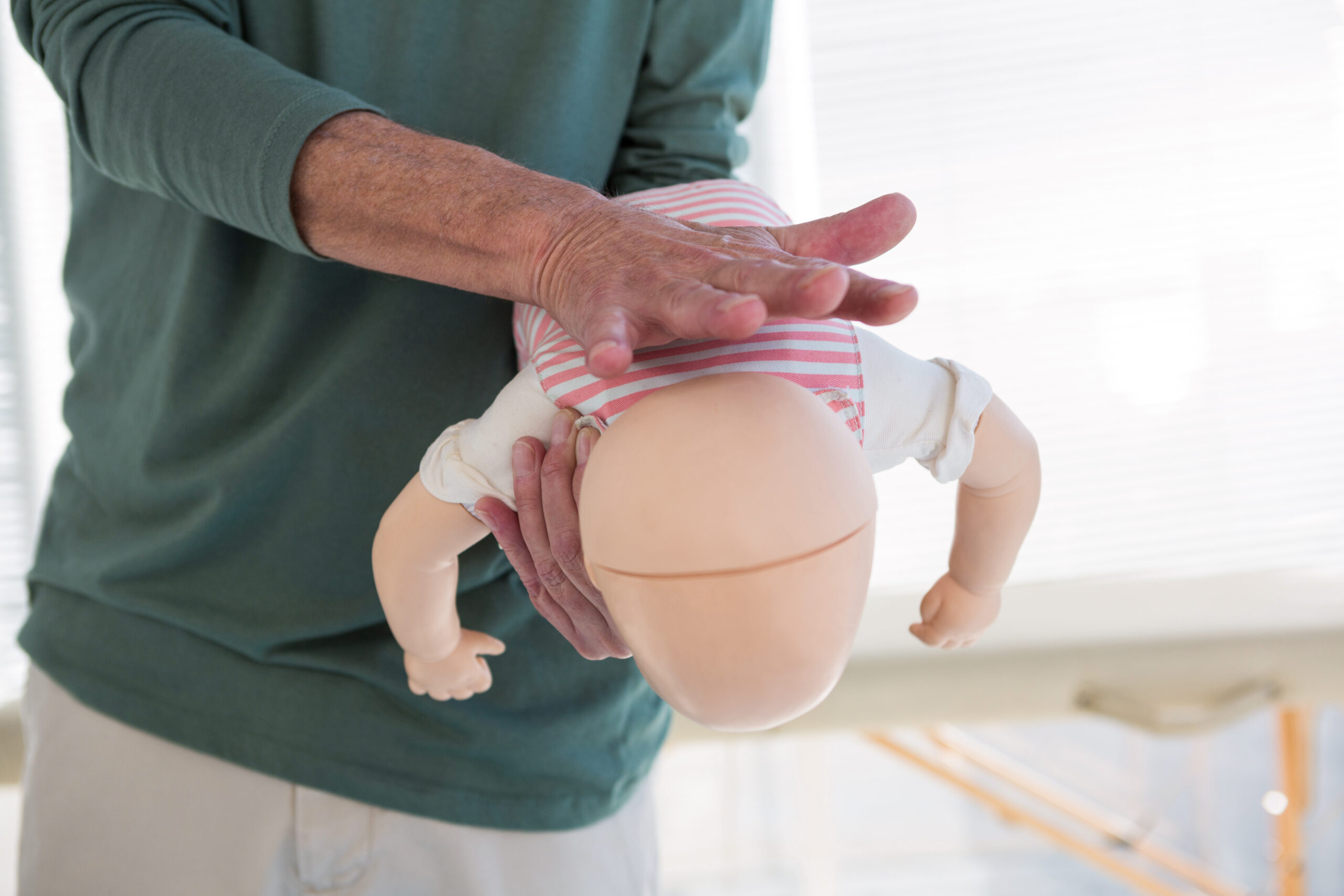 Paramedic demonstrating resuscitation on a infant dummy to rescue from suffocation