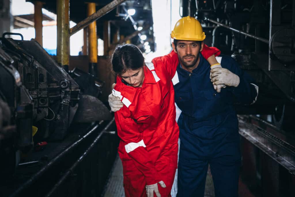 fire warden assisting injured female warehouse worker